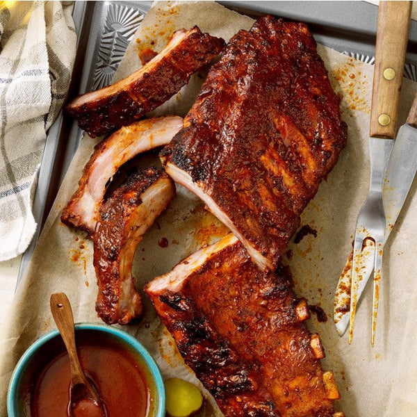 Le estan añadiendo bbq al costillar de cerdo una vez ya preparado 