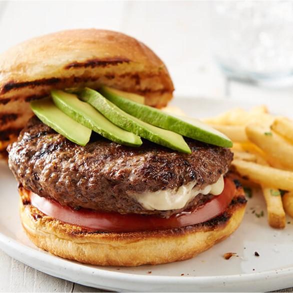 Nuestra hamburguesa artesanal lista para ser servida, acompañada con palta, queso y tomate.
